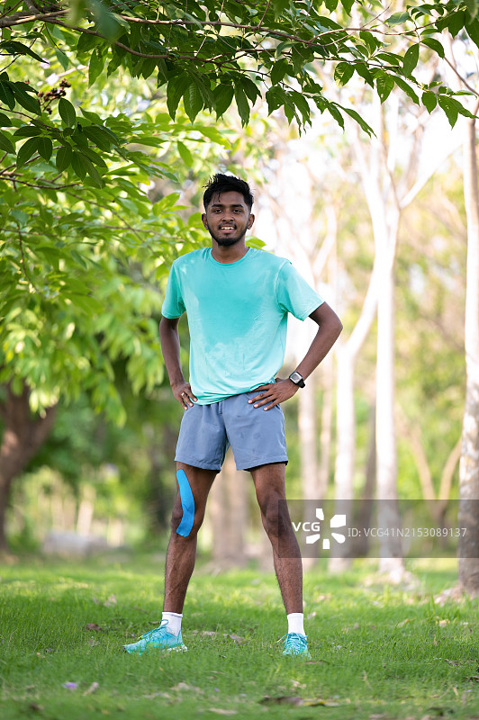 身穿鲜艳运动服在户外自信摆姿势的年轻运动员图片素材