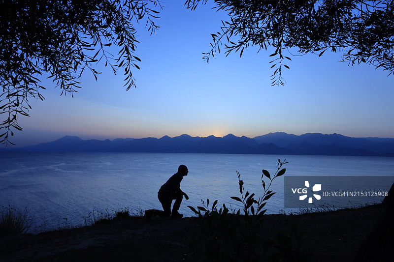 日落时分站在湖边的男子剪影图片素材