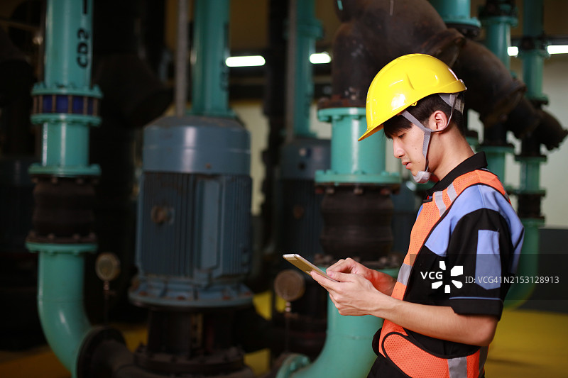 戴安全帽的维修工程师在控制室检查流程图片素材