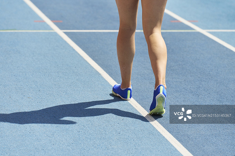 运动装女人在田径跑道上行走图片素材