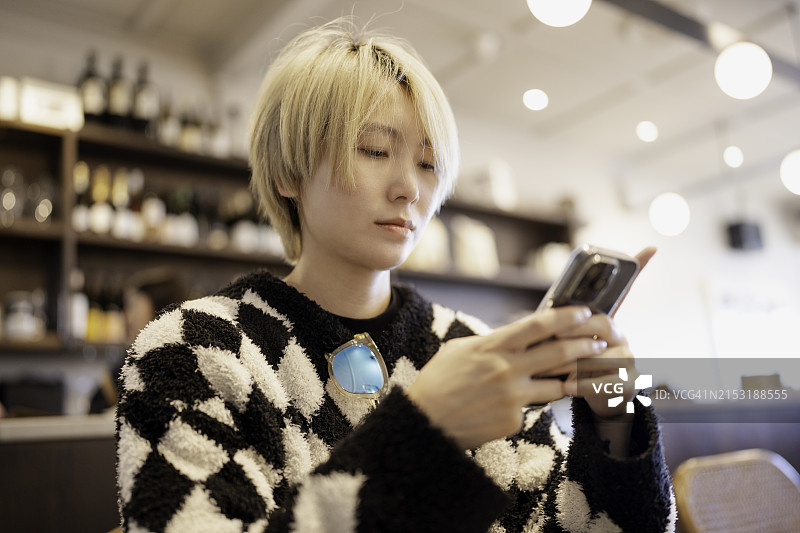在明亮室内查看手机的染发亚洲女性图片素材