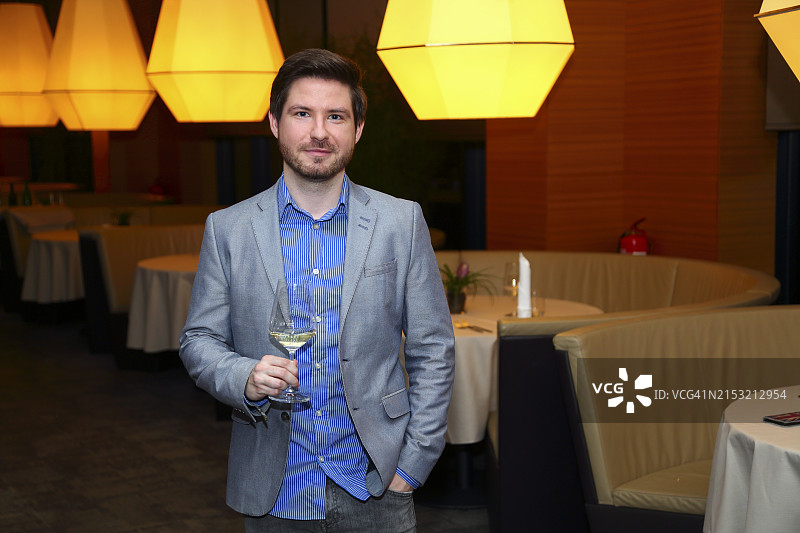 在餐厅里手持一杯葡萄酒的男人图片素材