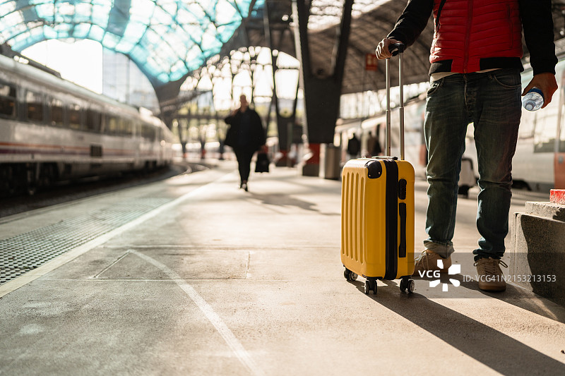 男子在火车站拖着黄色行李箱行走图片素材