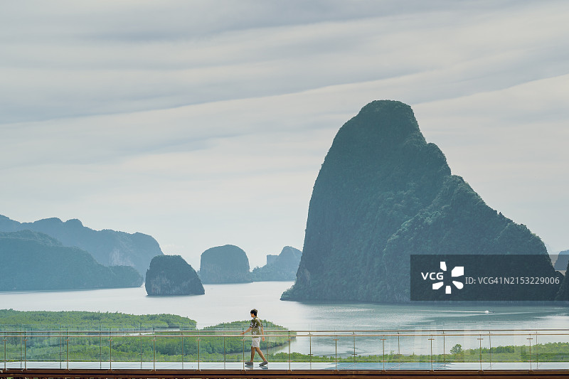 日出时分，高空玻璃地板悬浮桥观山景，男人们走在玻璃桥上。图片素材