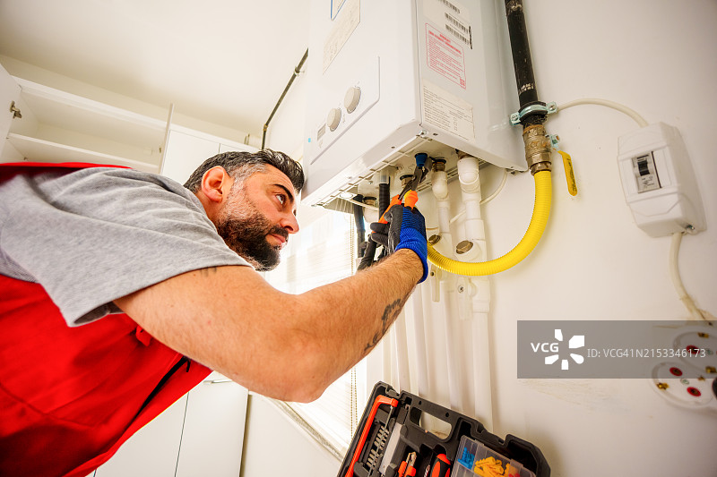 用扳手修理燃气锅炉的男人图片素材
