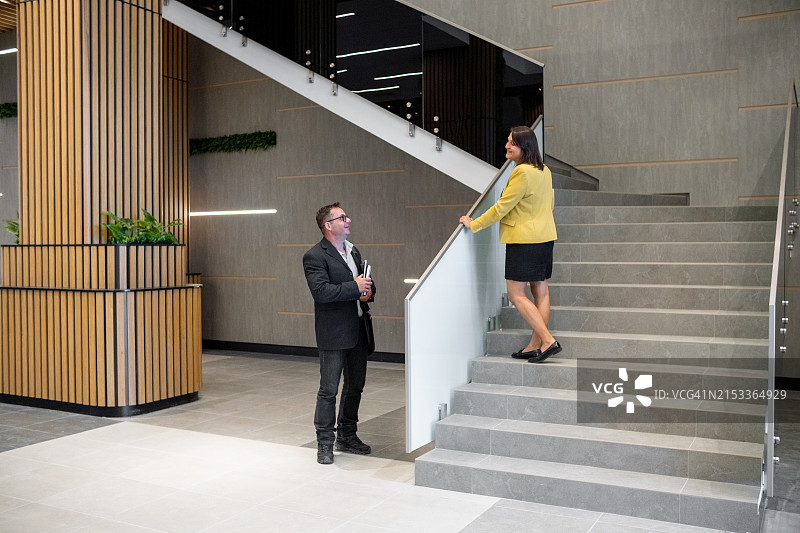 商务休闲装的商人和女商人在商务大楼台阶上交谈。图片素材