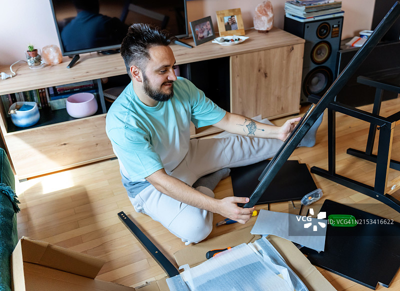 成年男子在现代室内组装家具图片素材