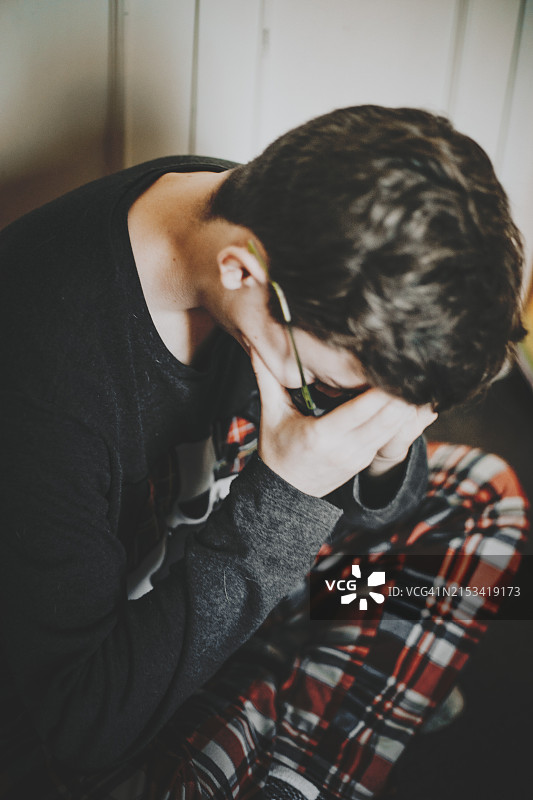 男青少年捂住头部，感到身体或精神上的疼痛图片素材