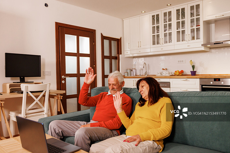 快乐的老年夫妇在家用笔记本电脑进行视频通话图片素材