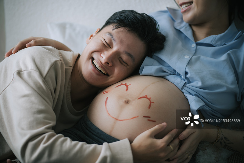 快乐的亚洲中国夫妇感受着准妈妈的胎动图片素材