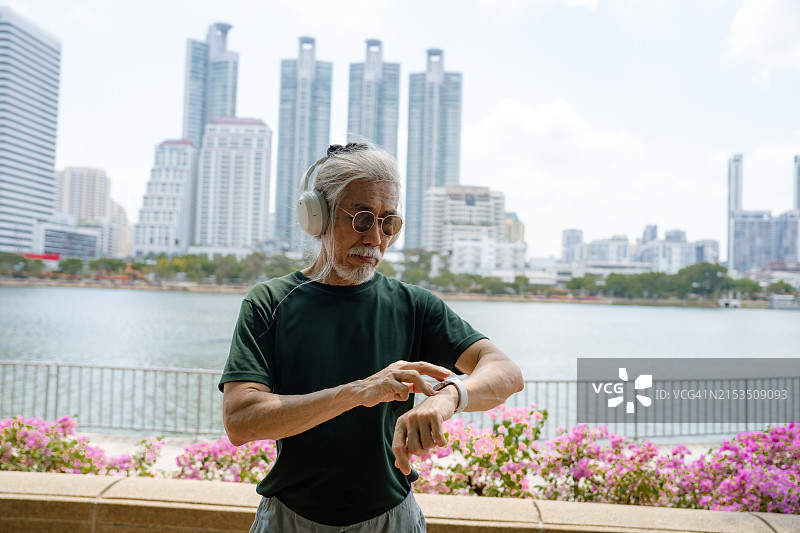 亚洲老年人在城市地区使用智能手表查看心率，结合音乐和科技图片素材