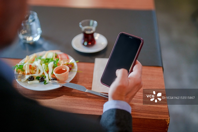 酒店早餐室内使用手机的商务人士特写图片素材