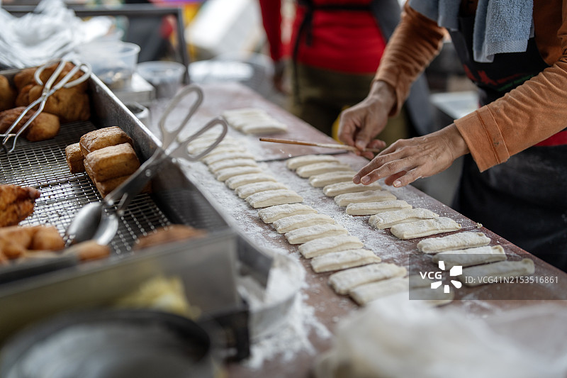 一位街头摊贩在街边摊位制作中国油条图片素材
