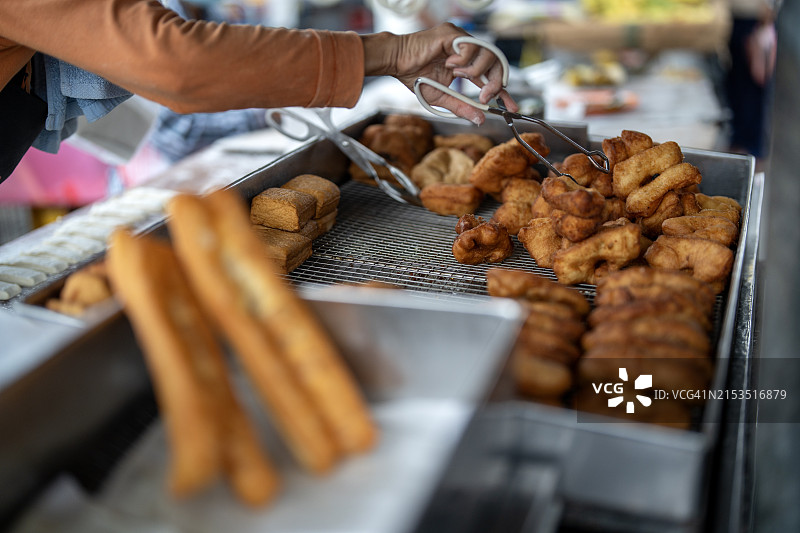 一位街头摊贩在街边摊位制作中国油条图片素材