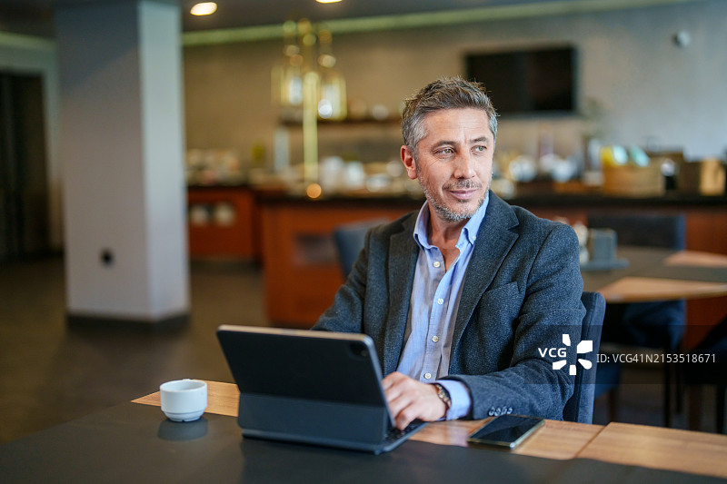 男人在酒店餐厅的餐桌旁使用平板电脑图片素材