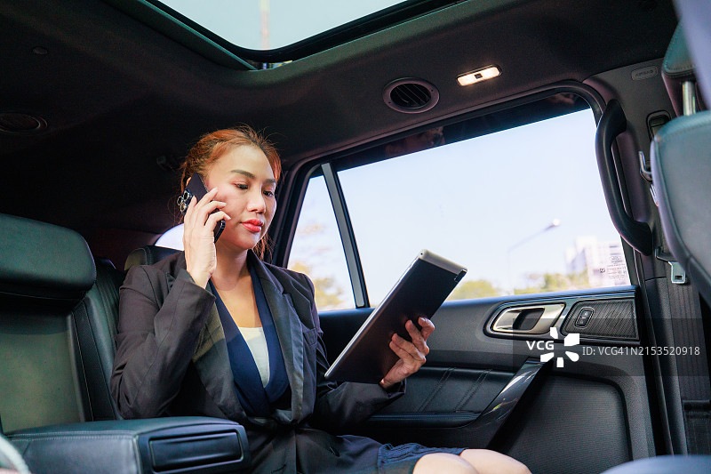 在途中的企业沟通：亚洲女商人用车载手机进行商务洽谈图片素材