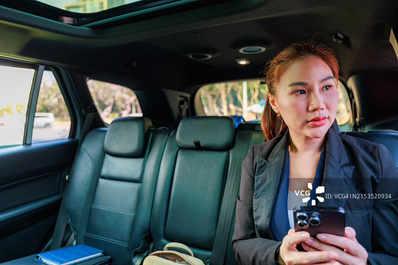 在途中的企业沟通：亚洲女商人用车载手机进行商务洽谈图片素材