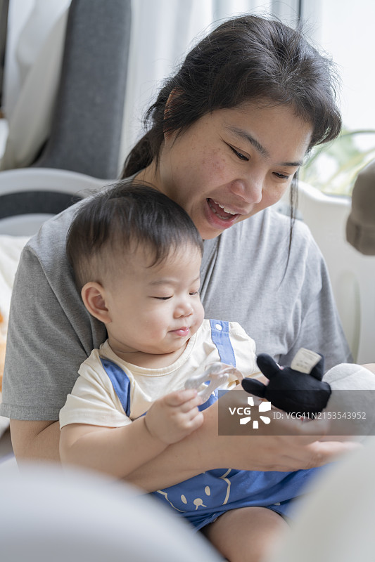 快乐的亚洲母亲与幼儿在婴儿床中玩耍，充满爱意和正能量图片素材