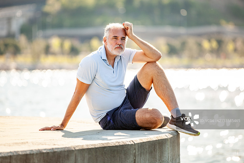 独自坐在码头边缘的中年男人图片素材