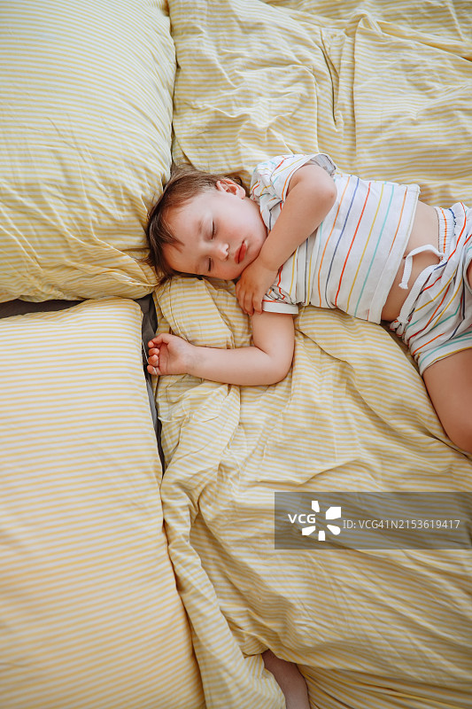 午睡的宁静：幼儿放松地躺在宽敞的床上，面颊胖乎乎的，有益于儿童的健康睡眠图片素材