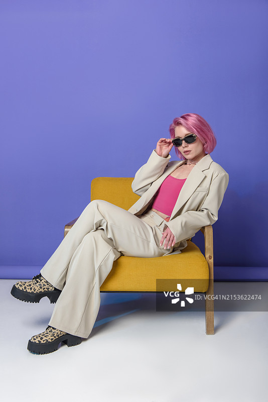 穿着彩色服装坐在黄色椅子上的美丽女人图片素材