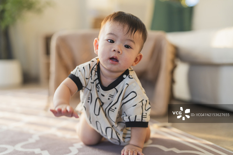 快乐的亚洲宝宝在家里练习爬行，玩耍图片素材
