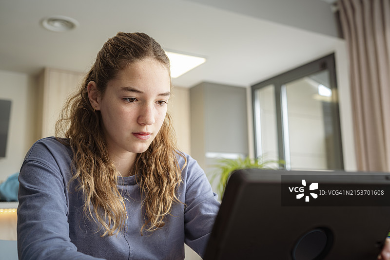 在家使用平板电脑进行电子学习的青少年女孩肖像图片素材