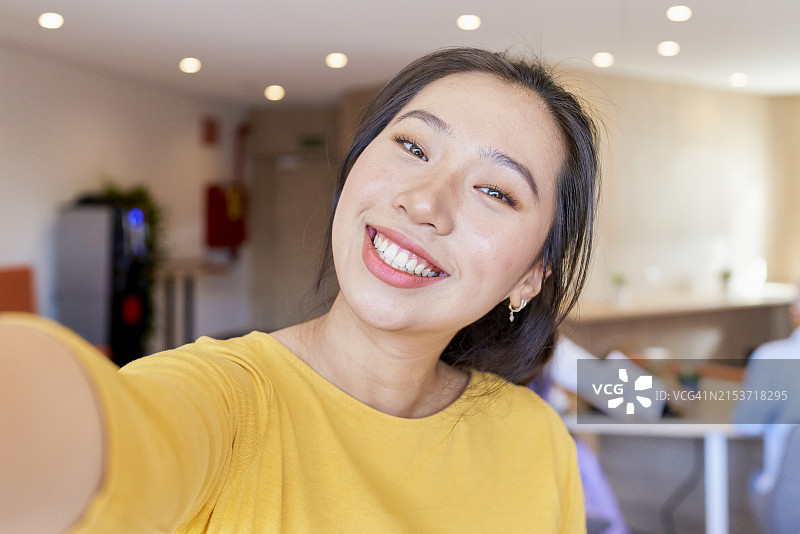 年轻亚洲女性手持相机微笑肖像（背景虚化）图片素材