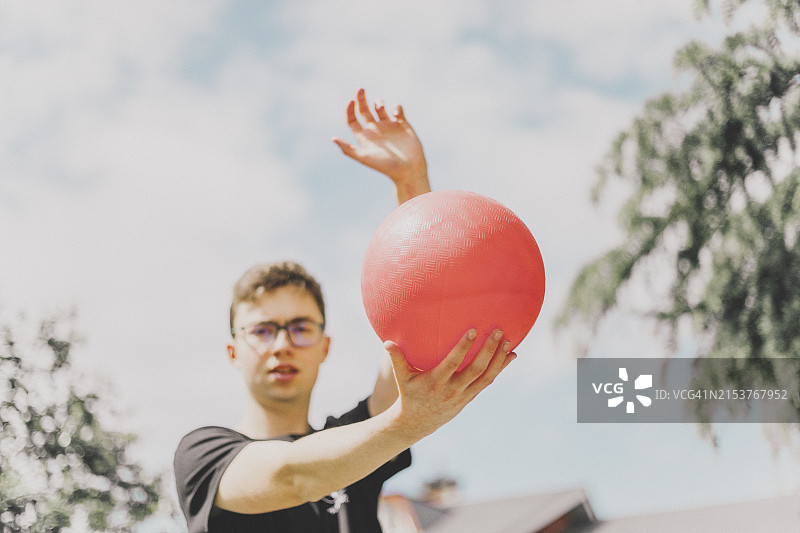 准备踢橙色球的青少年男子图片素材