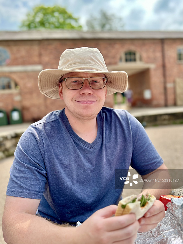 男人坐在长凳上吃三明治图片素材