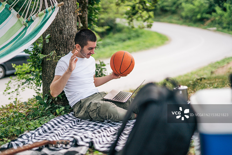 年轻男人在与父母视频通话时拿着篮球图片素材