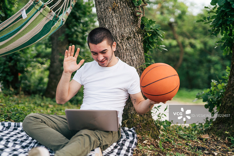 年轻男人在与父母视频通话时拿着篮球图片素材