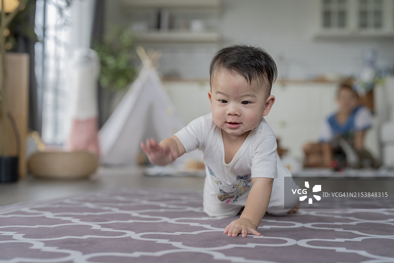 快乐的亚洲宝宝在家里练习爬行，玩耍图片素材