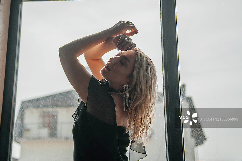 一幅年轻美女的肖像，背景是一扇有阳光和阴影的窗户。图片素材