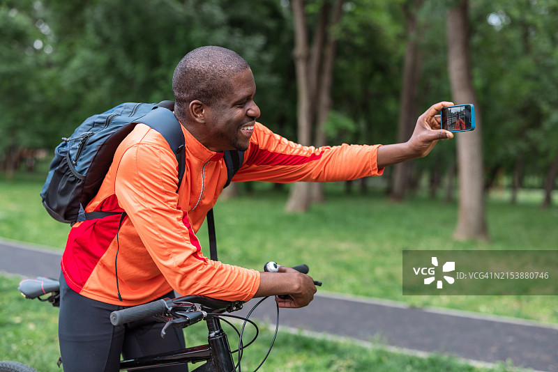 在公园骑自行车自拍的微笑男人图片素材