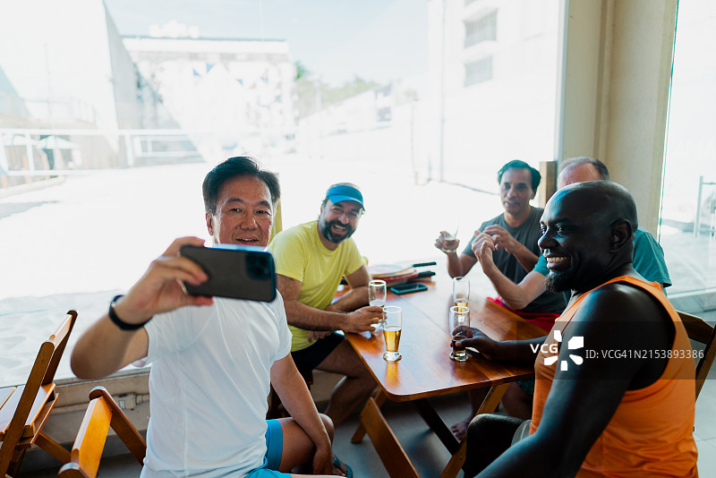 朋友们在沙滩网球后在餐厅自拍或拍摄图片素材