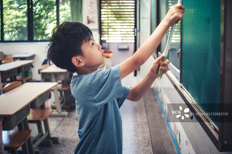 一位亚洲学生在教室里清洁黑板图片素材