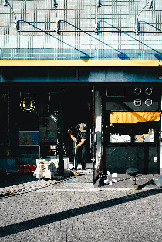 在晨光下清扫店面的人图片素材
