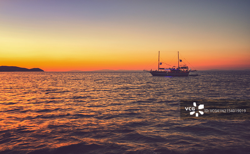 希腊岛屿美丽的日落下的游轮图片素材