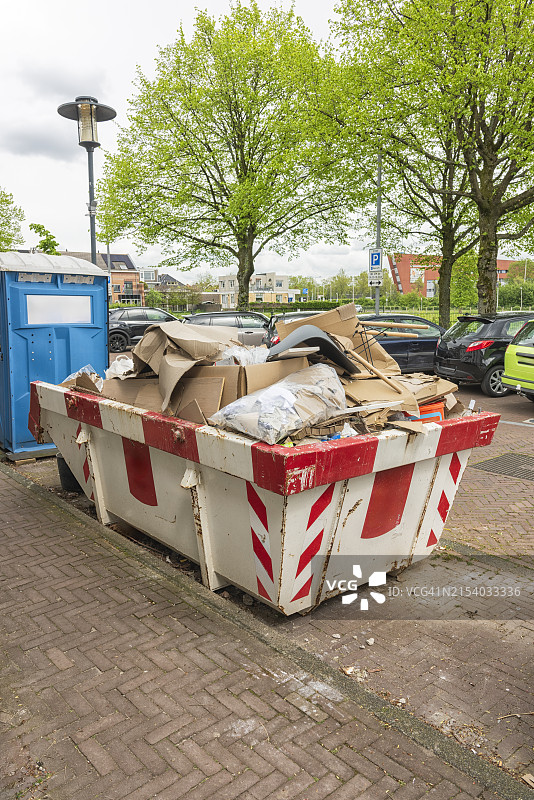 装满各种建筑废料的生锈的敞开式工业废料容器图片素材
