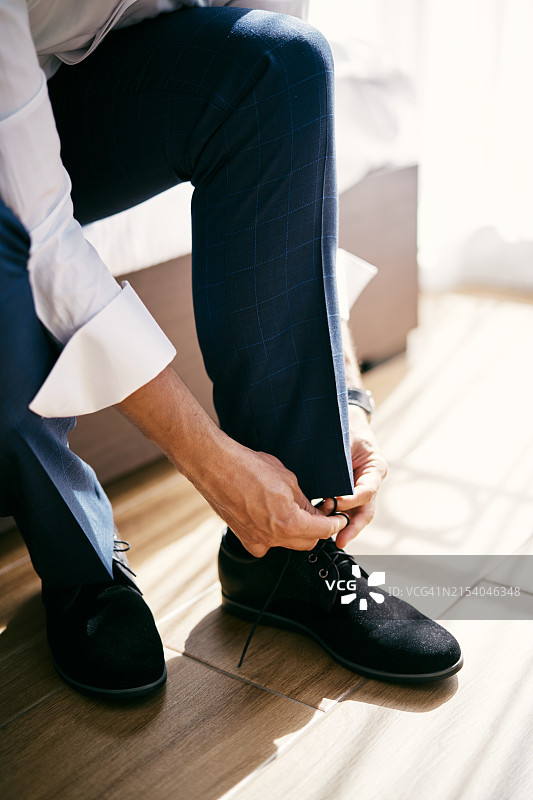 新郎坐在床上系鞋带（局部，无面孔）图片素材