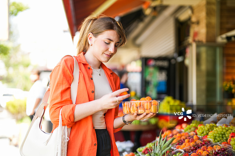 年轻金发女子在农贸市场购买水果和蔬菜图片素材