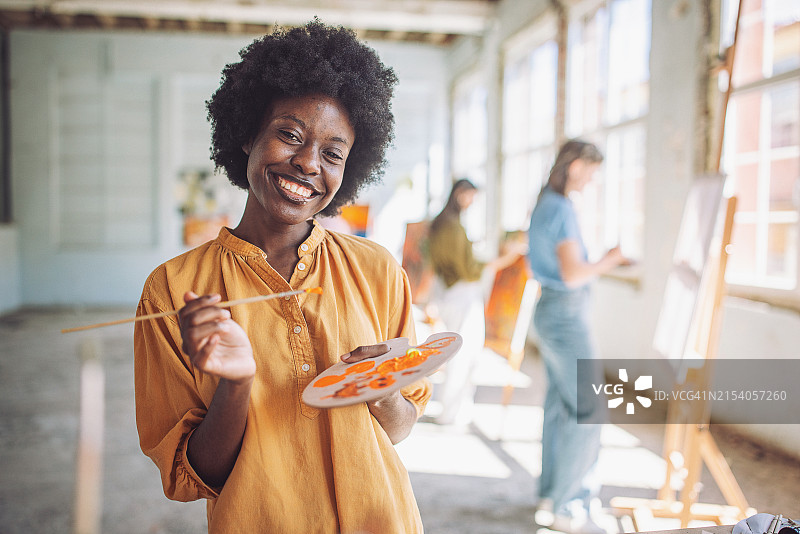 在艺术学校里，面带微笑的学生和富有创造力的老师一起上激动人心的艺术课图片素材
