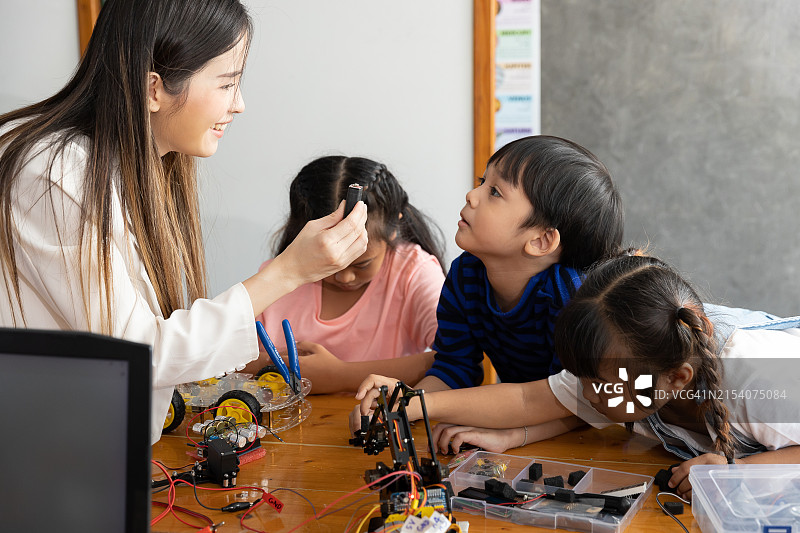 老师在STEM课堂上向好奇的年轻学生解释机器人组件图片素材