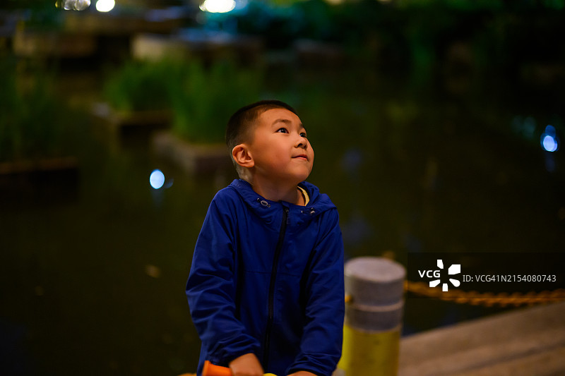 夜晚，一个亚洲小男孩在街上看图片素材