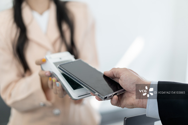 在酒店前台使用智能手机进行非接触式支付图片素材