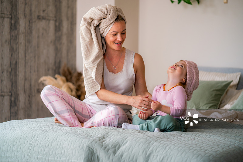 头上裹着毛巾坐在床上的母女图片素材