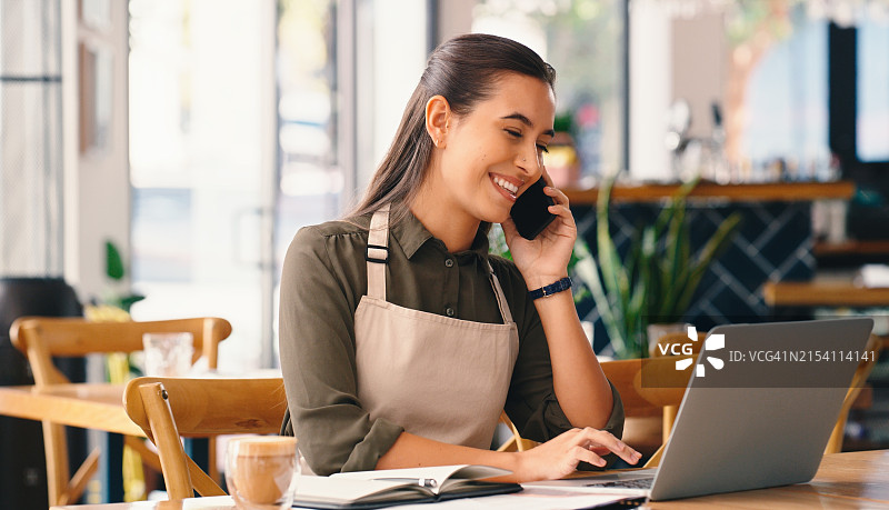 商务：咖啡师在咖啡馆用笔记本电脑接听电话，为顾客提供支持和外卖在线订单。专业的女服务员在咖啡店使用智能手机进行电子商务、供应链或清单管理图片素材