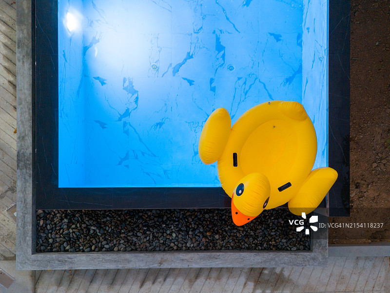 从上方俯视，蓝色水面上漂浮着黄色充气鸭子图片素材