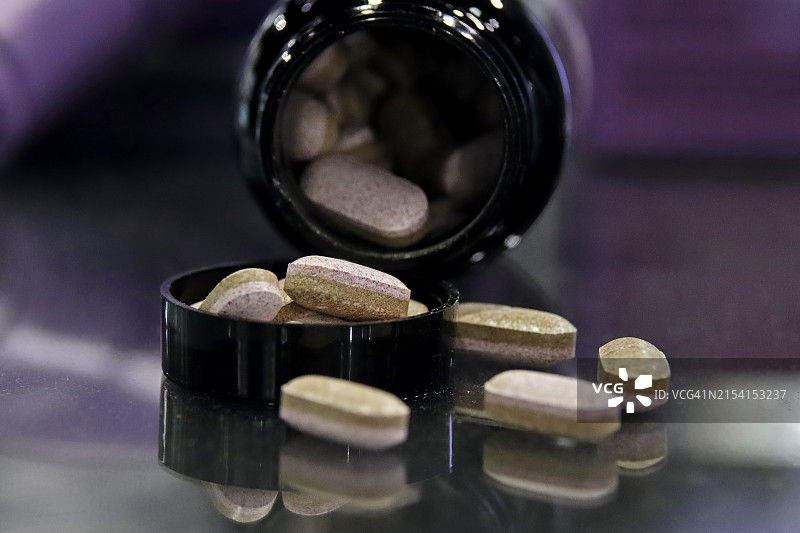 从打开的药瓶中洒落出来的药丸图片素材
